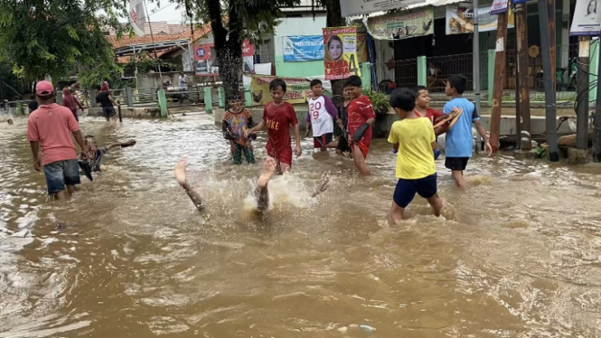 Anak-anak bermain air banjir di Simpang Mampang, Pancoran Mas, Kota Depok