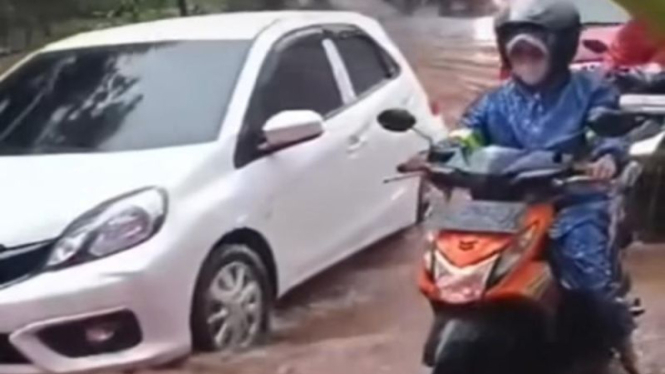 Pemotor melewati genangan banjir di Depok.