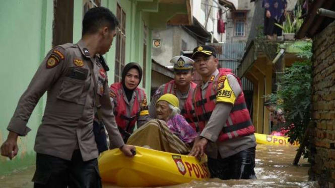 Aparat kepolisian saat mengevakuasi seorang lansia dari banjir di Rokan Hulu, Riau.
