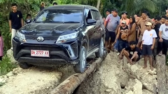 Mobil lewati jembatan batang kayu.