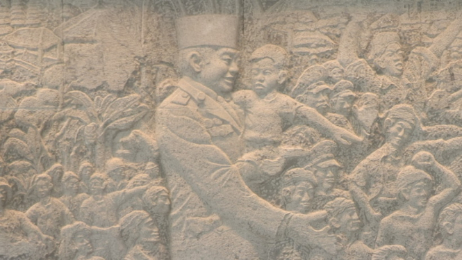 Relief Presiden RI pertama Sukarno sedang menggendong bayi dan di kelilingi rakyat Indonesia