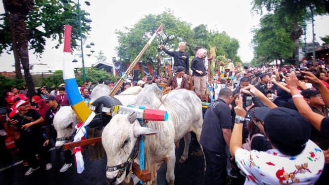 Capres nomor urut 3 Ganjar Pranowo didampingi istri dan anaknya naik gerobak sapi saat kirab menuju lokaso kampanye akbar Hajatan rakyat di Benteng Vastenburg, Solo