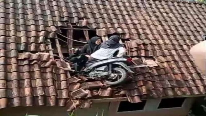 Dua bocah perempuan nyangkut dengan motornya di genteng rumah warga
