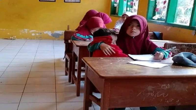 Bocah SD di Sinjai Nuraeni menggendong adiknya ke dalam kelas