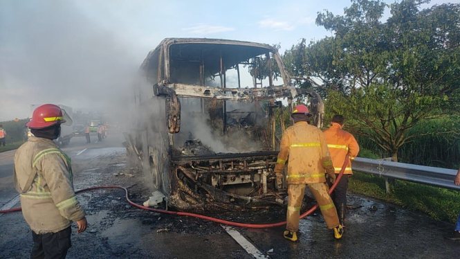 Petugas pemadam kebakaran saat memadamkan api yang melahap bus Pahala Kencana di Tol Jombang-Mojokerto. (Foto: PJR Ditlantas Polda Jatim)