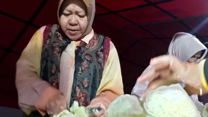 Menteri Sosial Tri Rismaharini alias Risma, Selasa dini hari, 21 Mei 2024, membantu relawan memasak di dapur umum tenda pengungsian korban banjir lahar hujan Gunung Marapi di Kabupaten Agam, Sumatra Barat.