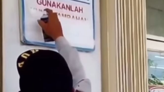 Seorang petugas Dishub menghapus papan parkir gratis di minimarket Lombok (Istimewa)