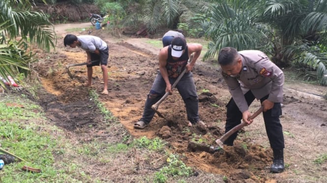 Aiptu Yanto bersama masyarakat membersihkan tanah pribadinya yang dihibahkan untuk jalan umum di  Dusun Pedomai, Desa Pemuar, Kecamatan Belimbing, Kabupaten Melawi, Kalbar.