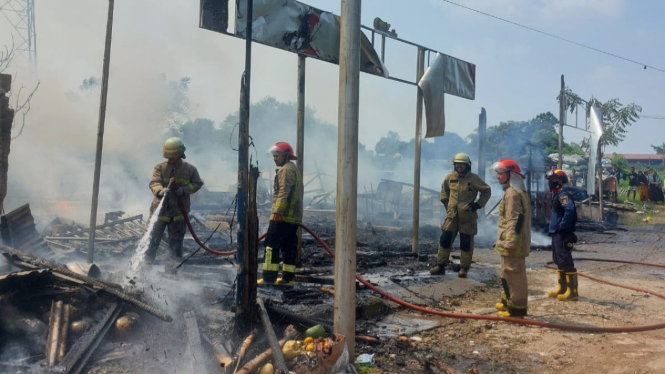 Petugas damkar melakukan pemadaman pada bangunan rumah makan dan 4 lapak buah yang terbakar di Tangerang.