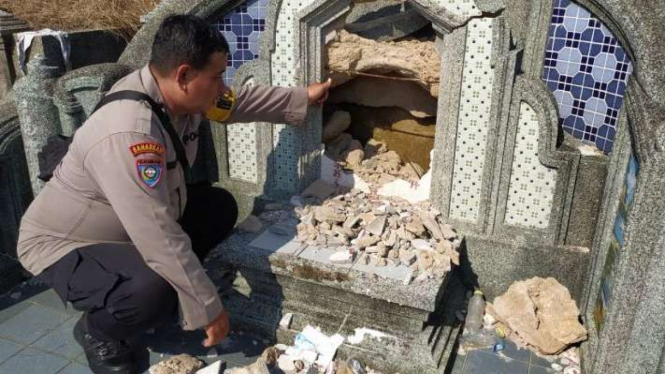 Petugas Bhayangkara Pembina Keamanan dan Ketertiban Masyarakat Parit Baru Aiptu Wangsit Indrianto menunjukkan nisan yang hancur rusak parah karena dirusak pelaku kejahatan di Makam Bhakti Suci, Kubu Raya, Kalimantan Barat.