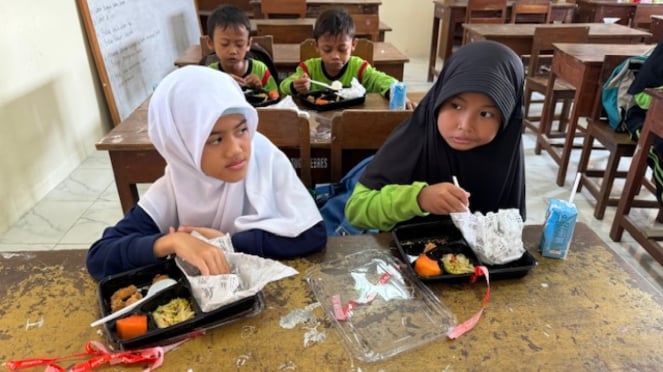 Los estudiantes de la escuela primaria Tugu comen arroz en cajas durante una prueba del programa de comidas nutritivas gratuitas en la escuela primaria Tugu el jueves 25 de julio de 2024.