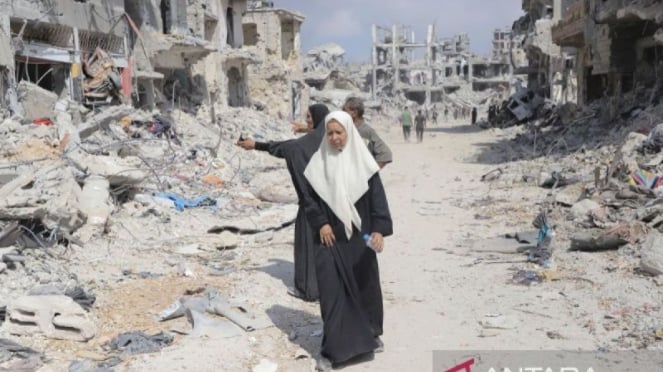 Moradores caminham por edifícios destruídos no assentamento Shujaya, em Gaza, Palestina