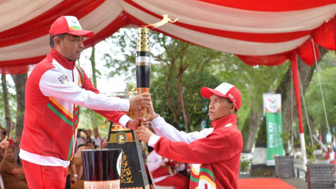 Pj Wali Kota Sabang menyerahkan api kirab PON kepada tim pelari untuk diarak. (istimewa)