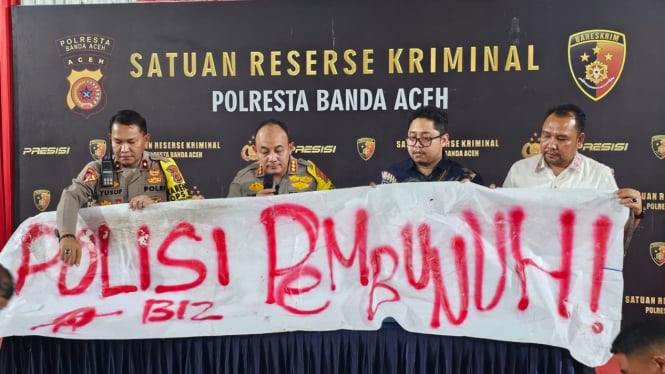 Polisi mengamankan pemasang spanduk bertuliskan 'polisi pembunuh'. VIVA/Dani Randi