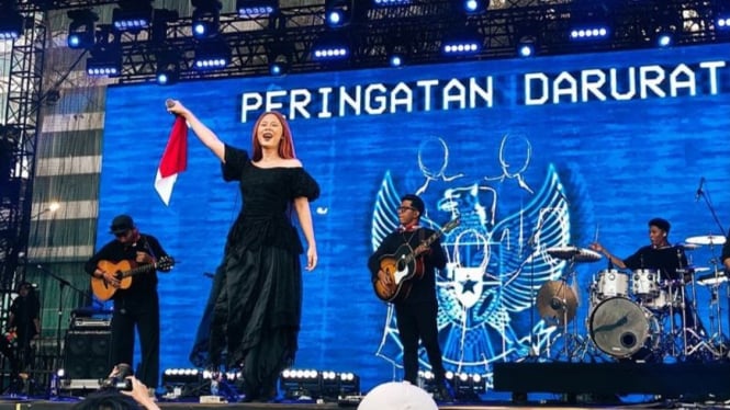 Aksi panggung penyanyi Nadin Amizah berlatar Peringatan Darurat garuda biru