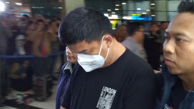 Tersangka HS alias Ahan saat tiba di Bandara Soetta.