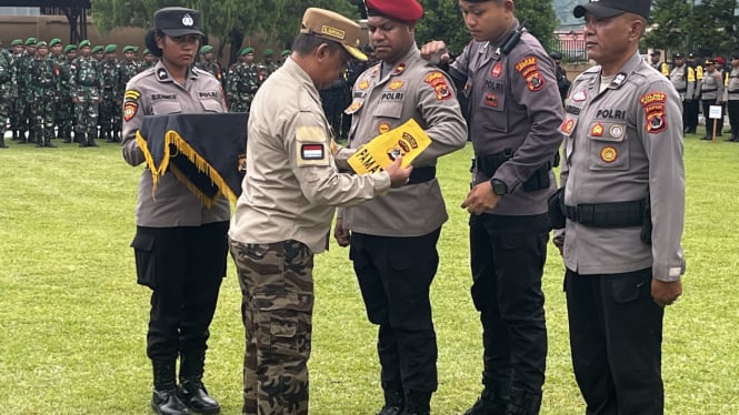 Pj Bupati Jayapura Semuel Siriwa saat memasang tanda pengamanan pilkada pada anggota polisi.