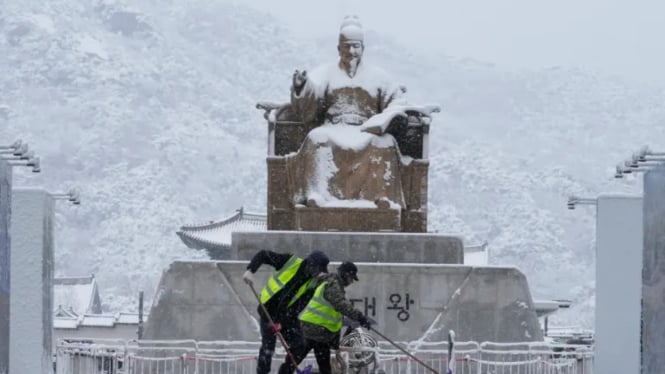 Pekerja membersihkan salju di depan patung Raja Sejong, Korea Selatan