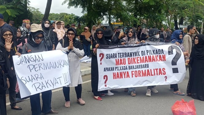 Perwakilan demonstran saat membentangkan spanduk terkait situasi Pilkada Banjarbaru 2024 