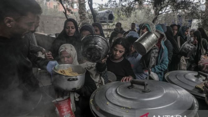 Warga mengantre menerima bantuan makanan di pusat distribusi pangan, Deir al-Balah, Jalur Gaza, Jumat, 20 Desember 2024.