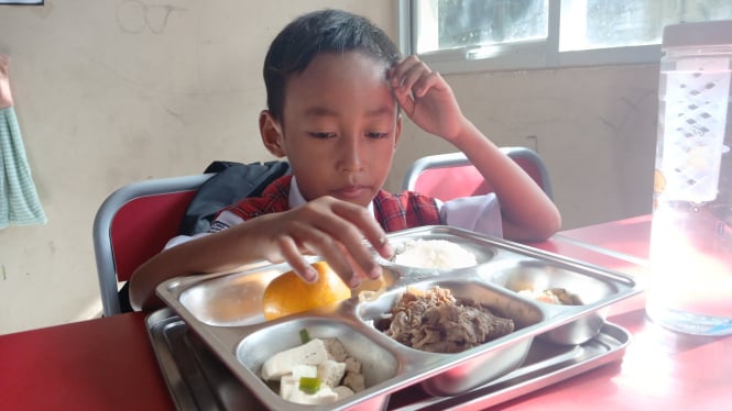 Gibran, siswa SDN Lengkong Gudang, Tangsel, saat menyantap menu MBG tanpa sendok dan garpu