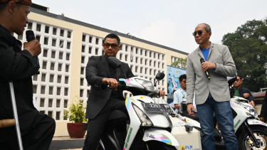 Iin Sodikin (kiri), seorang tuna daksa yang tergabung dalam kelompok Perkumpulan Penyandang Disabilitas Indonesia (PPDI) Garut yang akif di kelompok PELITA BERSAMA saat menjelaskan spesifikasi motor konversi listrik kepada pejabat PLN