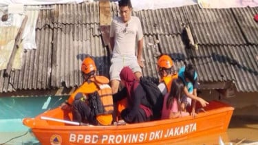 Petugas saat mengevakuasi warga terdampak banjir di Jakarta, Minggu (6/7/2025).