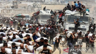 Varios residentes llevan la bolsa de masa del camión a la asistencia humanitaria en Gaza